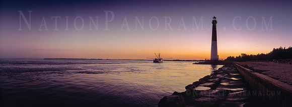 Barnegat Lighthouse at sunrise with fishing boat.