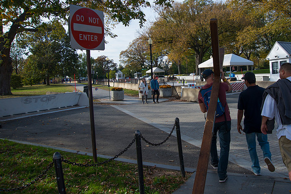 Man with cross walks around The White House during election day.